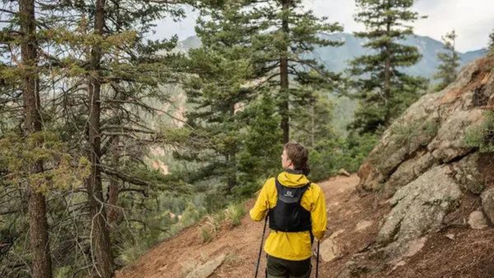 a lady wearing a yellow jacket hiking